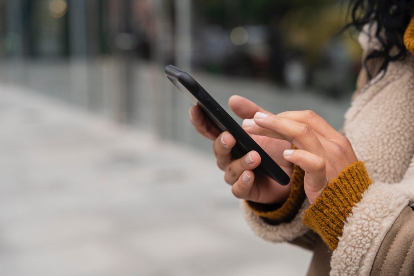 Eine Person hält ein Smartphone und tippt darauf, mit einer neutralen Umgebung im Hintergrund.